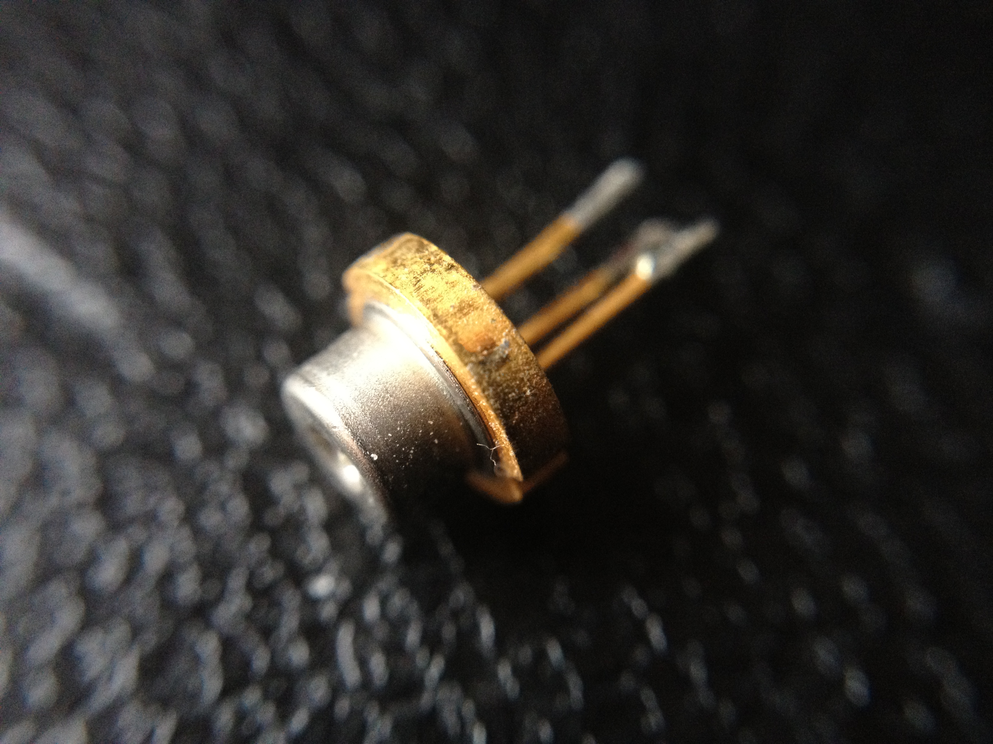 Macro shot of a bare laser diode TO-can package with its two leads, removed from the optical unit