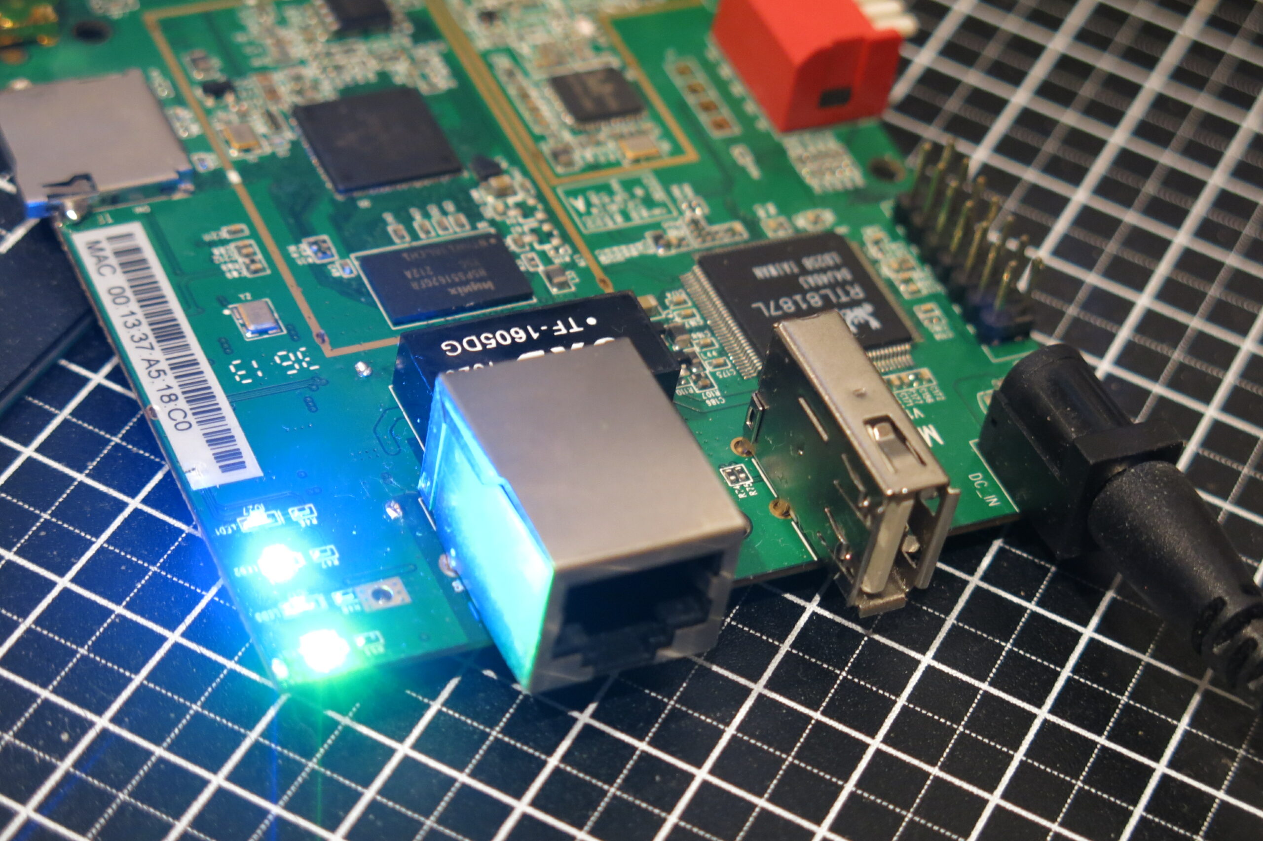 The repaired WiFi Pineapple Mark V board powered on with link LEDs lit, showing it fully functional